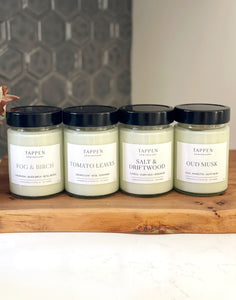 Four Tappen Apothecary candles on a wooden surface with a tiled wall background
