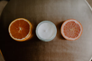 Top down photo of candle with a half cut grapefruit to the right and left