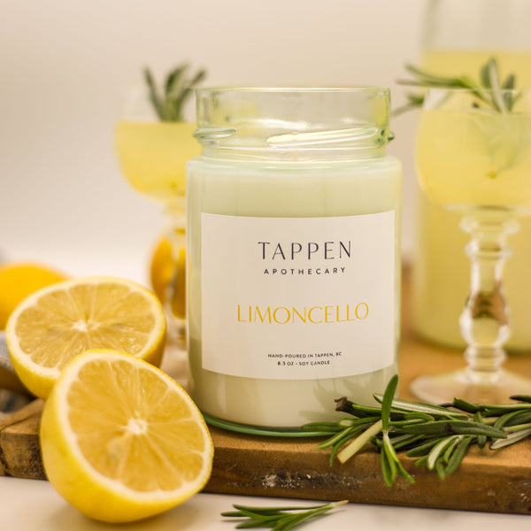 Candle labeled 'Tappen Apothecary Limoncello' with lemons and rosemary on a wooden board.